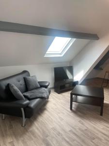 een woonkamer met een zwarte bank en een dakraam bij Superbe loft neuf - 1 chambre- face au Château -Netflix Canal Plus in Sedan