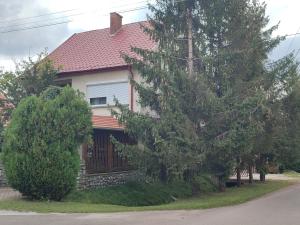 a house with a fence and trees in front of it at Roxana vendégház in Szilvásvárad