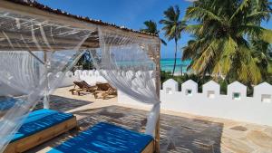 una marquesina en la playa con sillas azules y el océano en Kholle Villa en Jambiani
