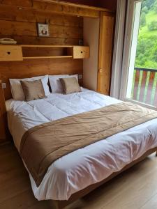 a large bed in a room with a window at Logis Hotels - Hôtel - Restaurant - Bar - Le Sapin Fleuri in Bourg dʼOueil
