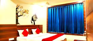 a bedroom with a bed and a window with blue curtains at Hotel Raj Residency in Bhopal
