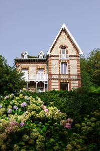 een groot bakstenen huis bovenop een heuvel met bloemen bij Villa Eliane - parking privé in Étretat