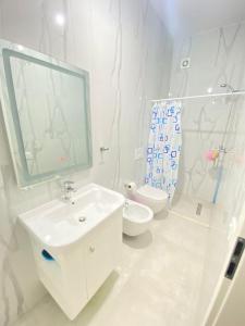 biała łazienka z umywalką i toaletą w obiekcie Hejli's Apartment w Tiranie