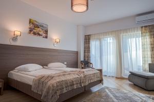 ein Schlafzimmer mit einem großen Bett und einem großen Fenster in der Unterkunft Hotel Cascada BAILE OLANESTI in Băile Olăneşti