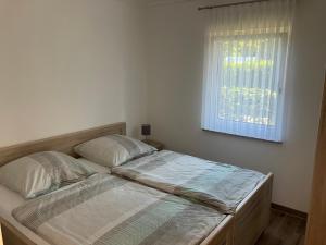 Bett in einem weißen Zimmer mit Fenster in der Unterkunft Havelstern Ketzin, Ferienhaus Barsch in Ketzin