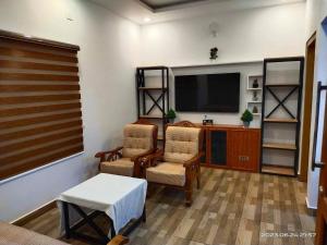 un soggiorno con due sedie e una TV a schermo piatto di Family Cottage at Merlys Fruit Garden, Thattekkad a Kotamangalam