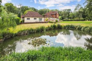 a house and a pond in front of a house at Woodland Cottage by inspirestays-com in Duneton