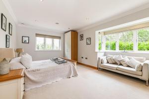 a white bedroom with a bed and a couch at Woodland Cottage by inspirestays-com in Duneton