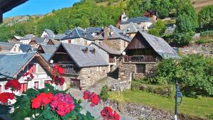 a small village with red flowers in the foreground at Logis - Hôtel - Restaurant - Bar - Le Sapin Fleuri in Bourg dʼOueil