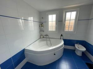 baño azul y blanco con bañera y aseo en Tokyo Rooms (El Playazo) - Habitación PREMIUM con baño privado en Almería