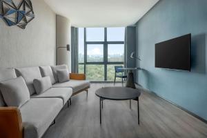 a living room with a couch and a tv on a wall at Four Points by Sheraton Urumqi in Ürümqi