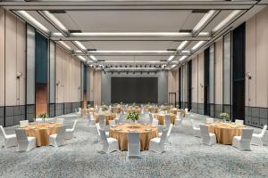 a large room with tables and white chairs and a projection screen at Four Points by Sheraton Urumqi in Ürümqi