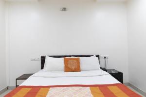 Una cama con una almohada naranja encima. en Hotel Amber Suite Near Mumbai Airport, en Bombay