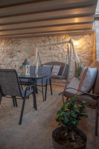 a patio with chairs and a table and a stone wall at Silva Luxury House in Mires (South Crete) in Moírai