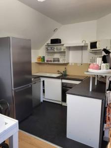 a kitchen with white cabinets and a stainless steel refrigerator at Du bon temps in Bôo-Silhen