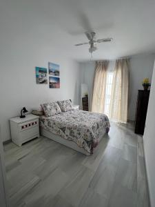 a white bedroom with a bed and a window at CASA RAUSER in Chipiona