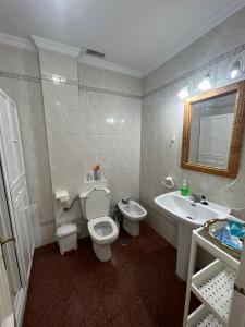 La salle de bains est pourvue de toilettes blanches et d'un lavabo. dans l'établissement CASA RAUSER, à Chipiona