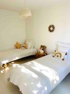 ein weißes Zimmer mit 2 Betten und einem Sofa in der Unterkunft Maison à l’orée du bois in Soustons