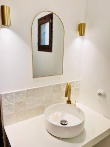 ein Badezimmer mit einem weißen Waschbecken und einem Spiegel in der Unterkunft Maison à l’orée du bois in Soustons