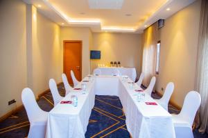 een lange tafel met witte tafels en stoelen in een kamer bij Best Western Plus The Athena Hotel Kampala in Kampala