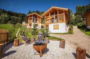 una cabaña en el bosque con sillas y una casa en Ferienhäuser Koralpe unicorn village en Wolfsberg