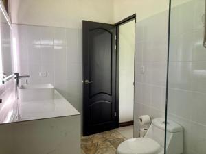a bathroom with a toilet and a sink and a black door at Eden Corcovado in San Pedrillo