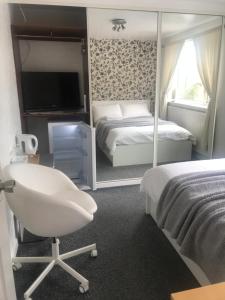 a bedroom with a bed and a chair and a television at fAiRy Dell Guesthouse with cozy lockable rooms, tv, free tea tray, wifi & parking in Oakenshaw