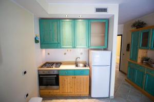 a kitchen with green cabinets and a white refrigerator at OASI BEACH Apartment in Buggerru