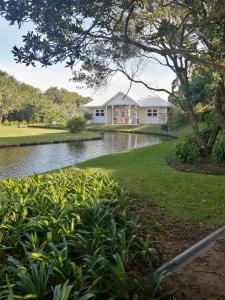 a house with a pond in front of it at Caribbean Estates Lakeview Villa in Port Edward