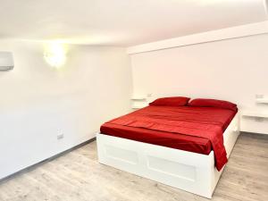 - une chambre blanche avec un lit et une couverture rouge dans l'établissement Appartamento Marco Simone, à Marco Simone