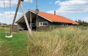 a house with an orange roof and a swing at Awesome Home In Hvide Sande With 4 Bedrooms And Sauna in Havrvig