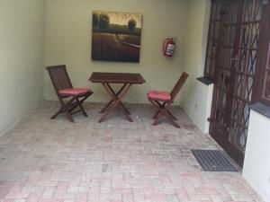 2 stoelen en een houten tafel in een kamer bij Hidden Villas Self Catering Guesthouse in East London