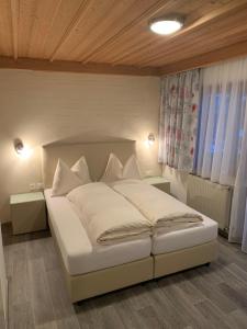 a bedroom with a large white bed with white pillows at Hotel Edi in Samnaun