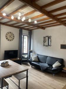 ein Wohnzimmer mit einem schwarzen Sofa und einer Uhr in der Unterkunft Superbe appartement face au Château - 2 chambres - Netflix/Canal+ in Sedan