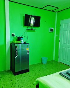 a green room with a tv and a green wall at ต้นกล้า รีสอร์ท 