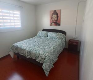a bedroom with a bed with a green and white blanket at Hospedaje Nuevo Amanecer in Antofagasta