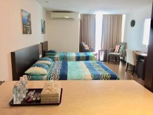 a hotel room with two beds and a table at Nazrins Studio Apartment KBCP in Kota Bharu +1 photo