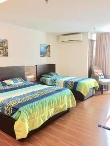 a bedroom with two beds and a chair at Nazrins Studio Apartment KBCP in Kota Bharu