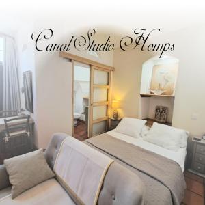 a bedroom with a bed and a couch and a mirror at La Maison du Canal - Canal Studio in Homps