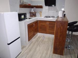 a kitchen with a white refrigerator and wooden cabinets at Residence Eliz in Kabrousse