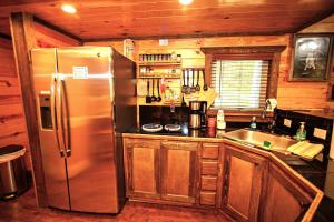 a kitchen with a stainless steel refrigerator and a sink at The Codex - Parker Creek Bend Cabins in Murfreesboro