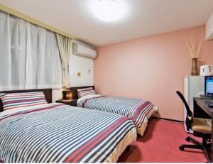 2 camas en una habitación con escritorio y ordenador en Hotel Yuni -Comfortable stay Star-Club iD, en Tokio