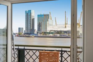 a balcony with a view of a river and buildings at Monthly Stays! 2 Bed Stunning Riverside Apartment in London