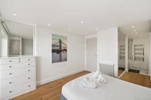a white bedroom with a bed and a dresser at Monthly Stays! 2 Bed Stunning Riverside Apartment in London