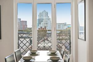 a dining room with a table and chairs and a window at Monthly Stays! 2 Bed Stunning Riverside Apartment in London