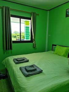 a green bedroom with a bed with two towels on it at ต้นกล้า รีสอร์ท 