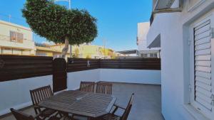 a wooden table and chairs on a balcony with a tree at STAY Napa Velvet Apartment in Ayia Napa