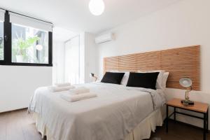 a white bedroom with a large bed with towels on it at Fliphaus Santa Fe 5100 - 3 Bd Pool & Bbq in Buenos Aires