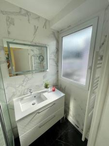 La salle de bains est pourvue d'un lavabo, d'un miroir et d'une fenêtre. dans l'établissement Appartement vue Saint Joseph, au Havre