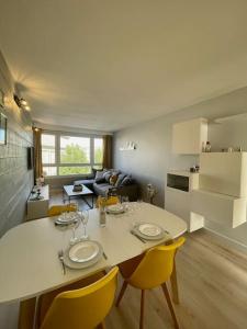 a kitchen and living room with a table and yellow chairs at Appartement vue Saint Joseph in Le Havre